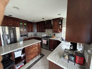 A modern kitchen with dark wood cabinets, stainless steel appliances, and a granite countertop.