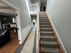 Un escalier recouvert d’une moquette à motifs, avec des marches en bois et des balustrades blanches.