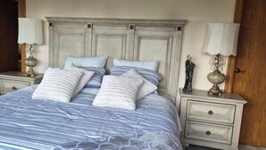 A bed with a striped bedspread, two bedside tables with lamps, and a wooden headboard. - - Blue Harbor Luxury Estate with Private Pool (Chemainus)