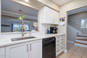A kitchen with white cabinets, a dishwasher, a coffee maker, and a plant. - 3-bed/2-bath Townhouse, Near Hospital & Parks (Troy)