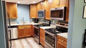 A kitchen with wooden cabinets, stainless steel appliances, a microwave, a coffee maker, and a dishwasher. - 6 Bedroom - 5.5 Bath - Second Tier (Climax Springs)