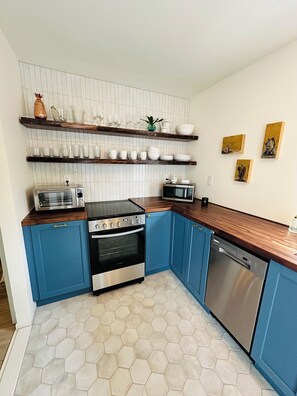 A kitchen with blue cabinets, a microwave, a toaster, and a dishwasher.