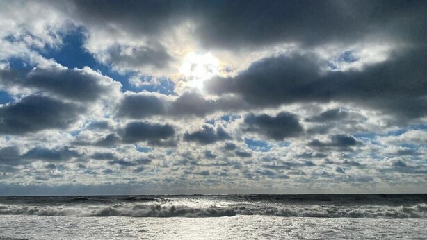 A view of the ocean with waves and a cloudy sky.