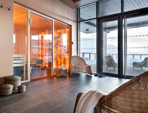 A modern interior with a glass door leading to a wooden room, wicker furniture, and a view of a snowy landscape.