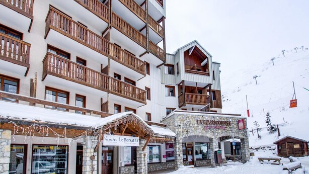 Un edificio de varios pisos con balcones, una entrada de piedra y señalización que dice 'Le Borsat IV'.