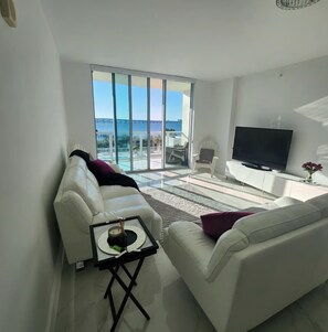 Ein modernes Wohnzimmer mit einem weißen Sofa, einem Couchtisch und einem Flachbildfernseher.
