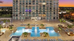A high-rise hotel with a pool area, multiple balconies, and a sunset view. - Waterfront apartment (Fort Myers)
