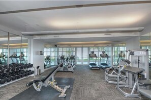 Ein Fitnessstudio mit Laufbändern, Crosstrainern, Kurzhanteln und Trainingsgeräten.
