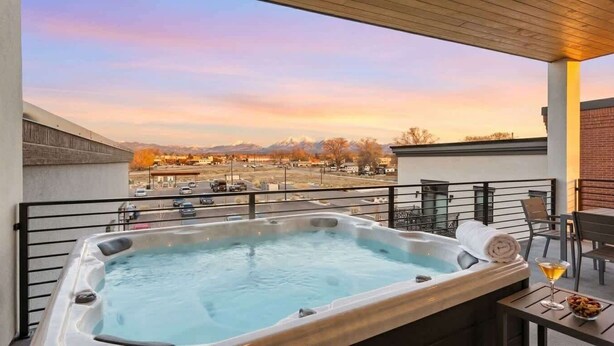 Ein Whirlpool auf einem Balkon mit Blick auf eine Stadtlandschaft und Berge.