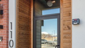 Ein moderner Eingangsbereich mit Glastür, Holzvertäfelung und der Zahl '110' an der Wand.