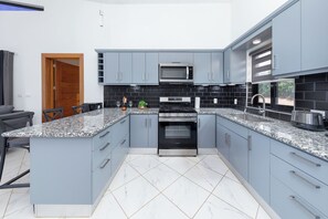 Eine moderne Küche mit grauen Schränken, einem schwarzen Backofen, einer Mikrowelle und einer Arbeitsplatte aus Granit.