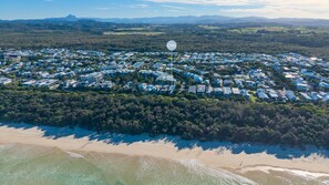 An aerial view of a coastal residential area with houses, a beach, and a clear sky. - The Boat House- Casuarina Beachfront Home (Casuarina)