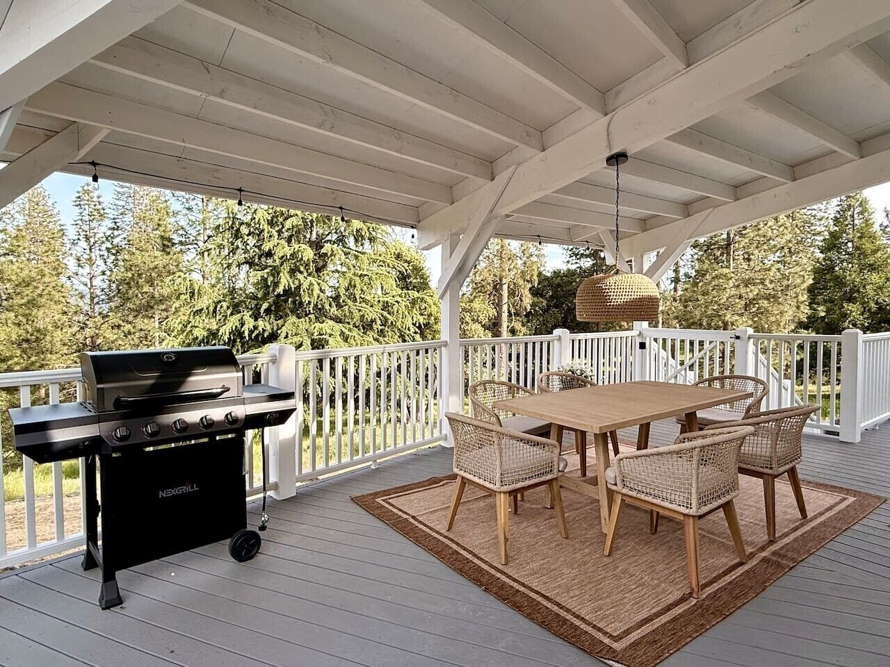 A covered outdoor patio with a grill, table, and chairs.