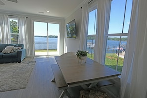 Ein modernes Wohnzimmer mit großem Fenster mit Seeblick, einem Esstisch und einem Sofa.