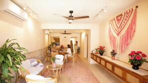 A spacious living area with a high ceiling fan, a dining table with chairs, and a decorative wall hanging. - La Gaviota, double room at Casa Sofia Centro, Vive Merida! (Mérida)