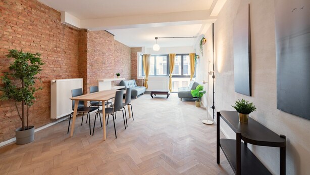 A modern living space with a dining area, seating, and a view of the city. - Grand Central Station 2br/14p Apartment (Antwerp)