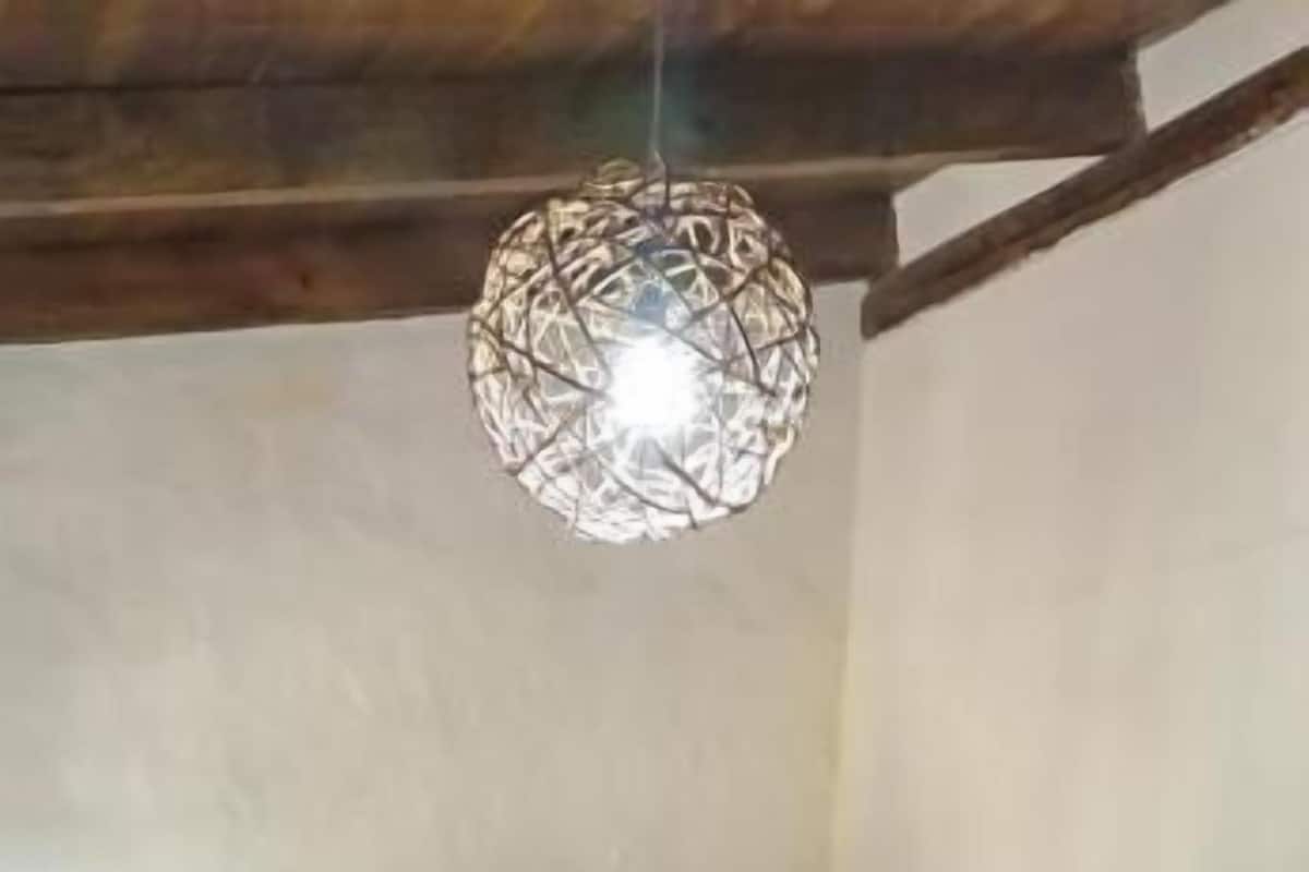 Camas literas con ropa de cama a rayas, una lámpara colgante y vigas de madera.