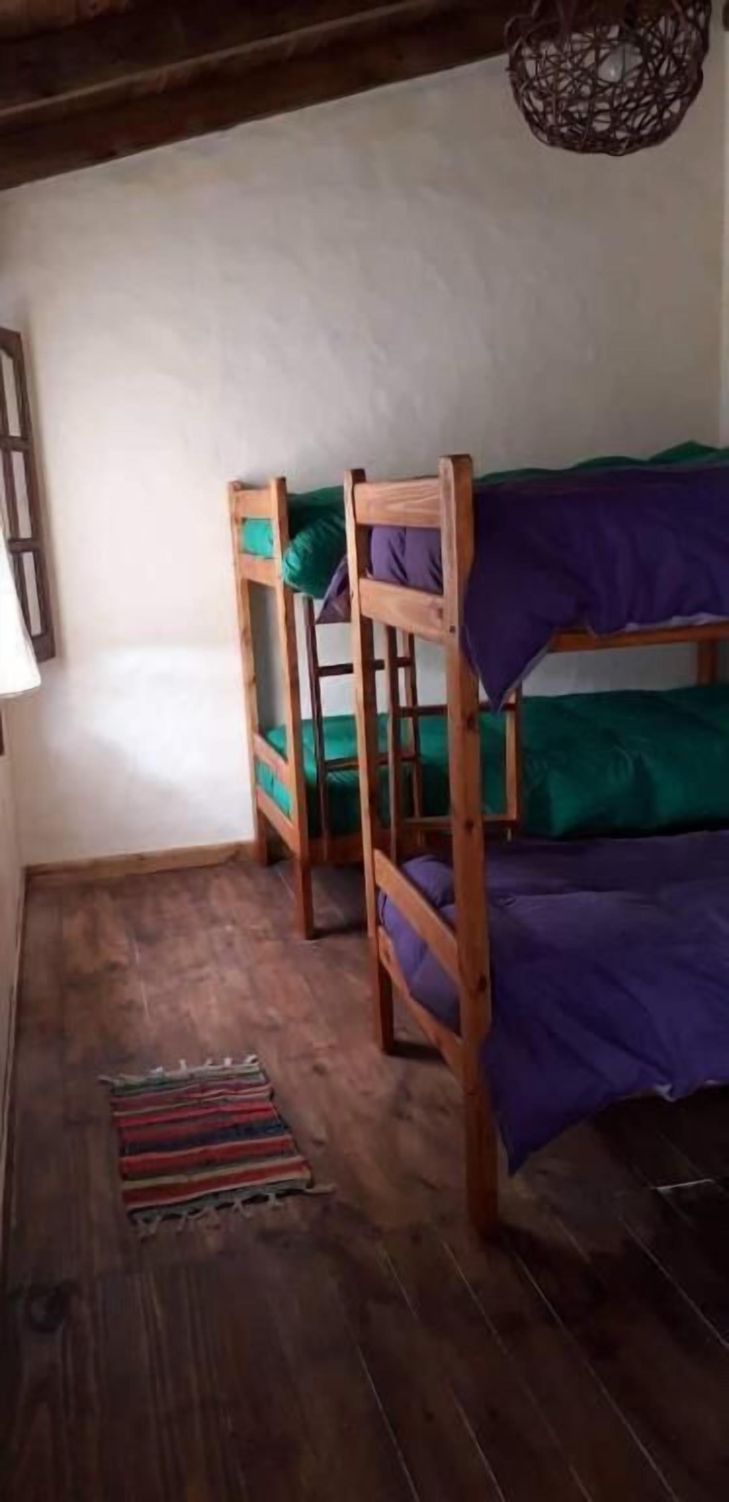 Una habitación con literas, una cesta colgante del techo y un tapete a rayas en el suelo.