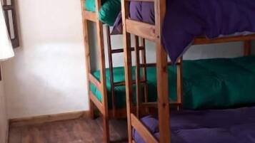 Una habitación con literas, una cesta colgante del techo y un tapete a rayas en el suelo.
