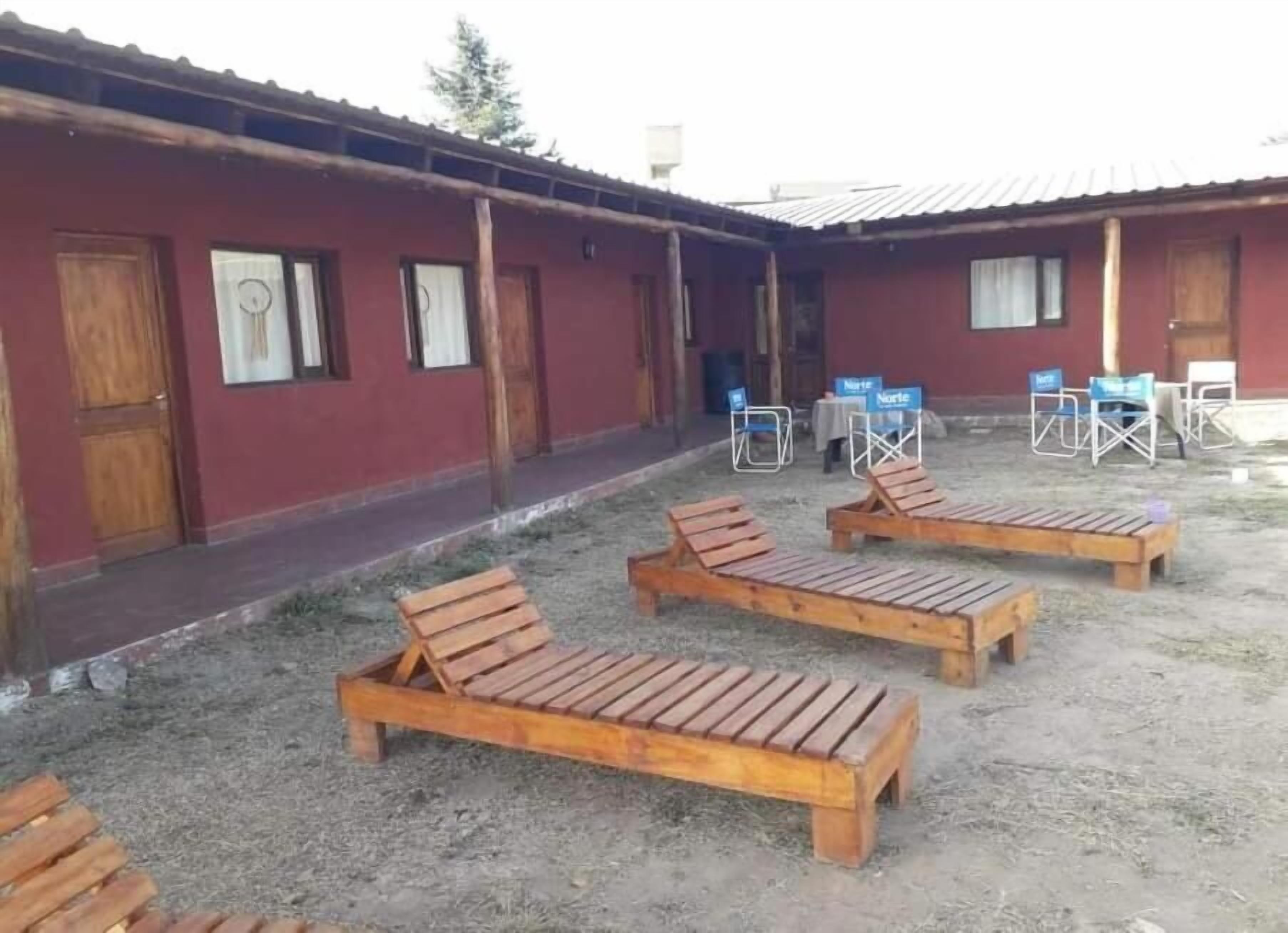 A building with a red exterior, wooden benches, and a covered outdoor area with chairs.