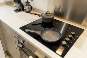 A kitchen with a stove, a frying pan, and a pot on the counter.