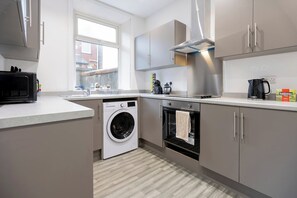 A modern kitchen with a washing machine, oven, and a window providing natural light. - Whole house for work crews, parking, 6 beds (Church)
