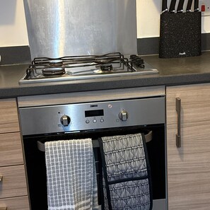 Eine Küche mit einem Gasherd, einem Backofen und einem Setz Messern auf der Arbeitsfläche.