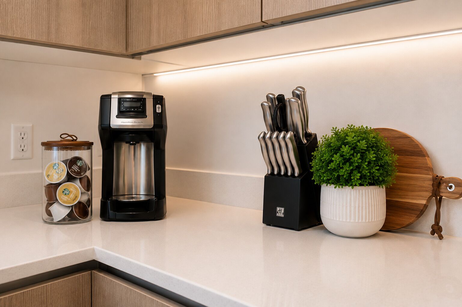 A kitchen counter with a coffee maker, a knife block, and a potted plant.