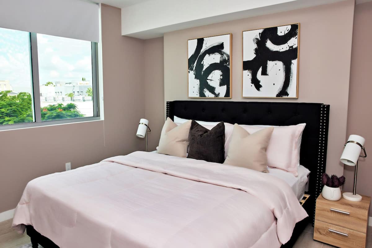 A bedroom with a bed, bedside lamps, and abstract art on the wall.