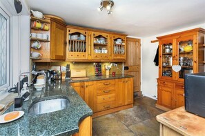 A kitchen with wooden cabinets, a granite countertop, and a sink.