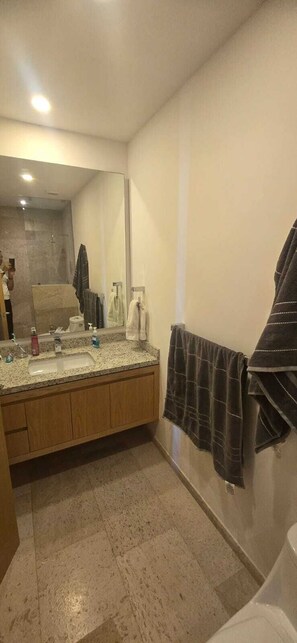 A bathroom with a sink, mirror, towel rack, and shower area. - Beautiful apartment with the best view of the Arch in Cabo San Lucas  (los cabos)