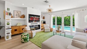 Un salon moderne doté d’une cheminée, d’un téléviseur à écran plat et offrant une vue sur une piscine.