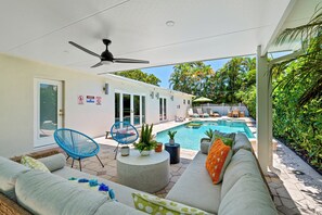 Ein Poolbereich im Freien mit Deckenventilator, einer Sitzgelegenheit mit Sofa und Sesseln sowie Blick auf den Pool.