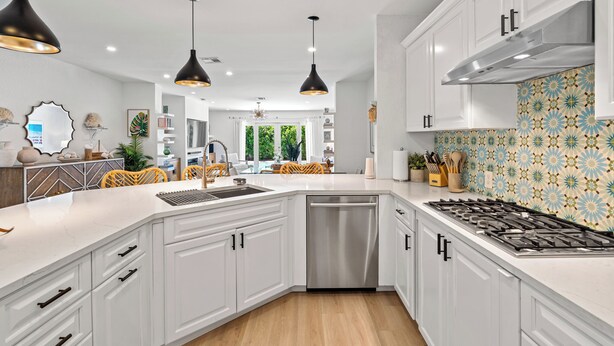 Une cuisine moderne avec des meubles blancs, un lave-vaisselle en acier inoxydable et une cuisinière à gaz.