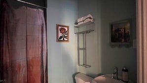 A bathroom with a toilet, sink, shower curtain, and a framed picture on the wall. - Delightful 1-bedroom suit in boutique guesthouse with AC in vibrant New York (New York)