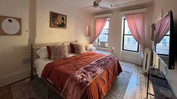 A bedroom with a bed, a ceiling fan, a radiator, and a window with curtains. - Delightful 1-bedroom suit in boutique guesthouse with AC in vibrant New York (New York)