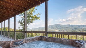 Ein Whirlpool auf einer Holzterrasse mit Blick auf die Berge.