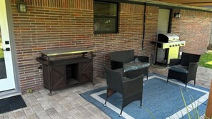 An outdoor patio with a brick wall, a grill, wicker furniture, and a blue rug. - Spacious 4-bedroom house in charming Houston area. (Houston)