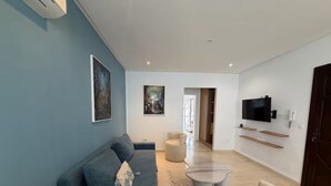 A modern living room with a blue sofa, a round coffee table, and a TV mounted on the wall. - Gammarth Blue Pearl (La Marsa)