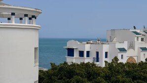 A coastal building with a white facade, blue accents, and a view of the sea. - Gammarth Blue Pearl (La Marsa)