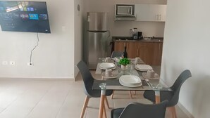 A modern dining area with a glass table, black chairs, and a TV mounted on the wall. - APARTMENT IN CANCUN WITH SWIMMING POOL IN A CONDOMINIUM (Cancún)