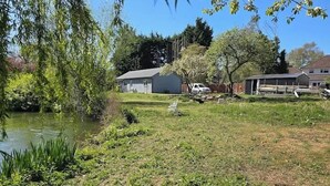 A residential area with a pond, a small shed, and a fenced yard.