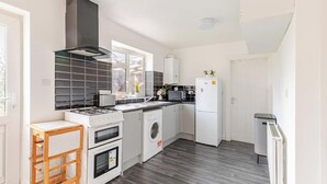 A modern kitchen with a gas stove, oven, microwave, and washing machine.