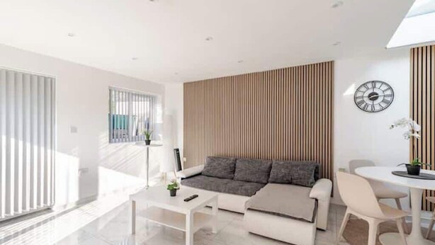 A modern living room with a sofa, coffee table, and a dining area with chairs and a table.