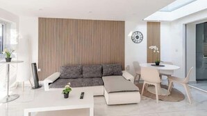 A modern living room with a sectional sofa, a round dining table, and a large window.