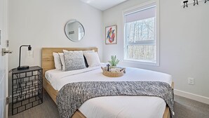A bedroom with a bed, bedside table, lamp, window, and artwork. - k211- AC, Pool/Hot Tub, Parking, BBQ, View (Canmore)