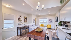 A modern kitchen with a dining area, white cabinetry, and a large window. - k211- AC, Pool/Hot Tub, Parking, BBQ, View (Canmore)