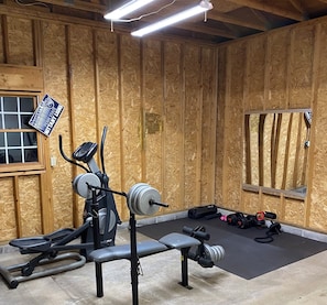 A gym with exercise equipment, a bench, and a mirror.