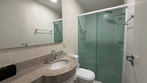 Une salle de bain avec un lavabo en granit, des toilettes, une douche en verre et un miroir.