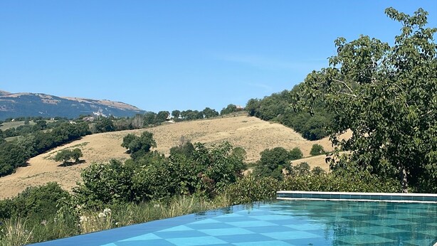 Une piscine à l’eau d’un bleu limpide, entourée d’une terrasse en pierre.